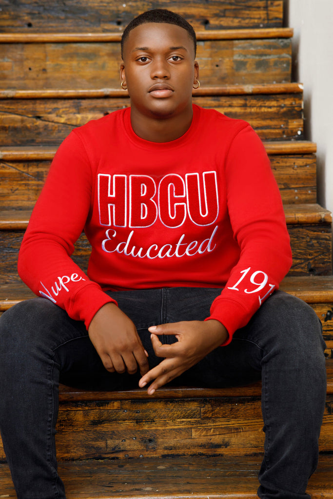 Man in red HBCU Nupe sweatshirt sitting on stairs.