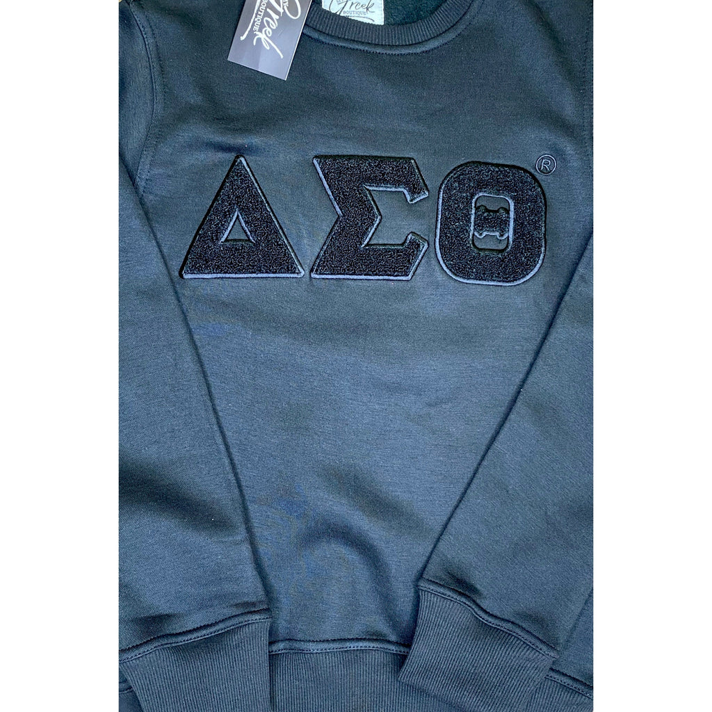 A woman wearing a Black sweatshirt with the letters  ΔΣΘ. Solid ΔΣΘ Chenille Sweatshirt, snugger fit if desired.