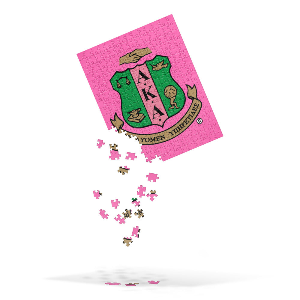 A pink puzzle piece with a green and pink logo. AKA Shield Jigsaw puzzle. Vibrant colors, semi-gloss finish. Can be used as wall decor in 252 pieces